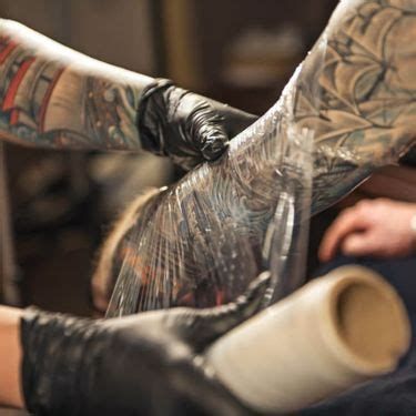 Tatuador fazendo curativo em uma tatuagem.